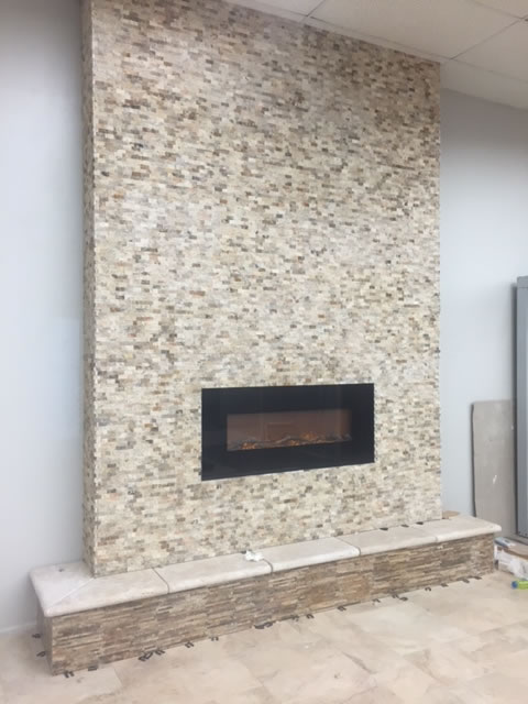 The fireplace is covered in 1x2 splitface scabos stone. The hearth features white travertine coping and polished scabos on the bottom. 